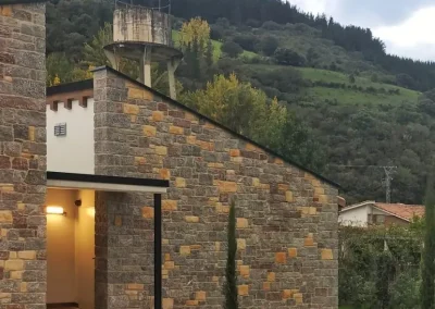 Fachada moderna de vivienda unifamiliar de piedra al atardecer
