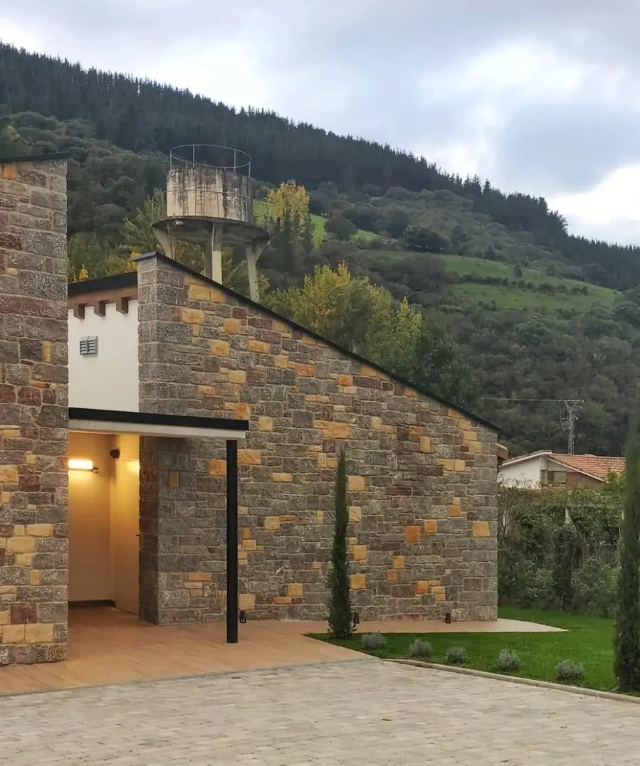 Fachada moderna de vivienda unifamiliar de piedra al atardecer
